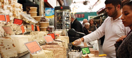 At the Jerusalem outdoor market, a vendor cuts samples of halvah. // © 2011 Mindy Poder F